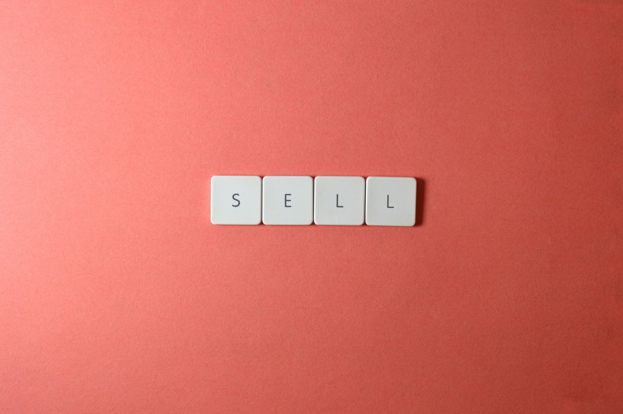 A close-up view of keyboard keys forming the word sell against a red backdrop, in a clean minimalist style.